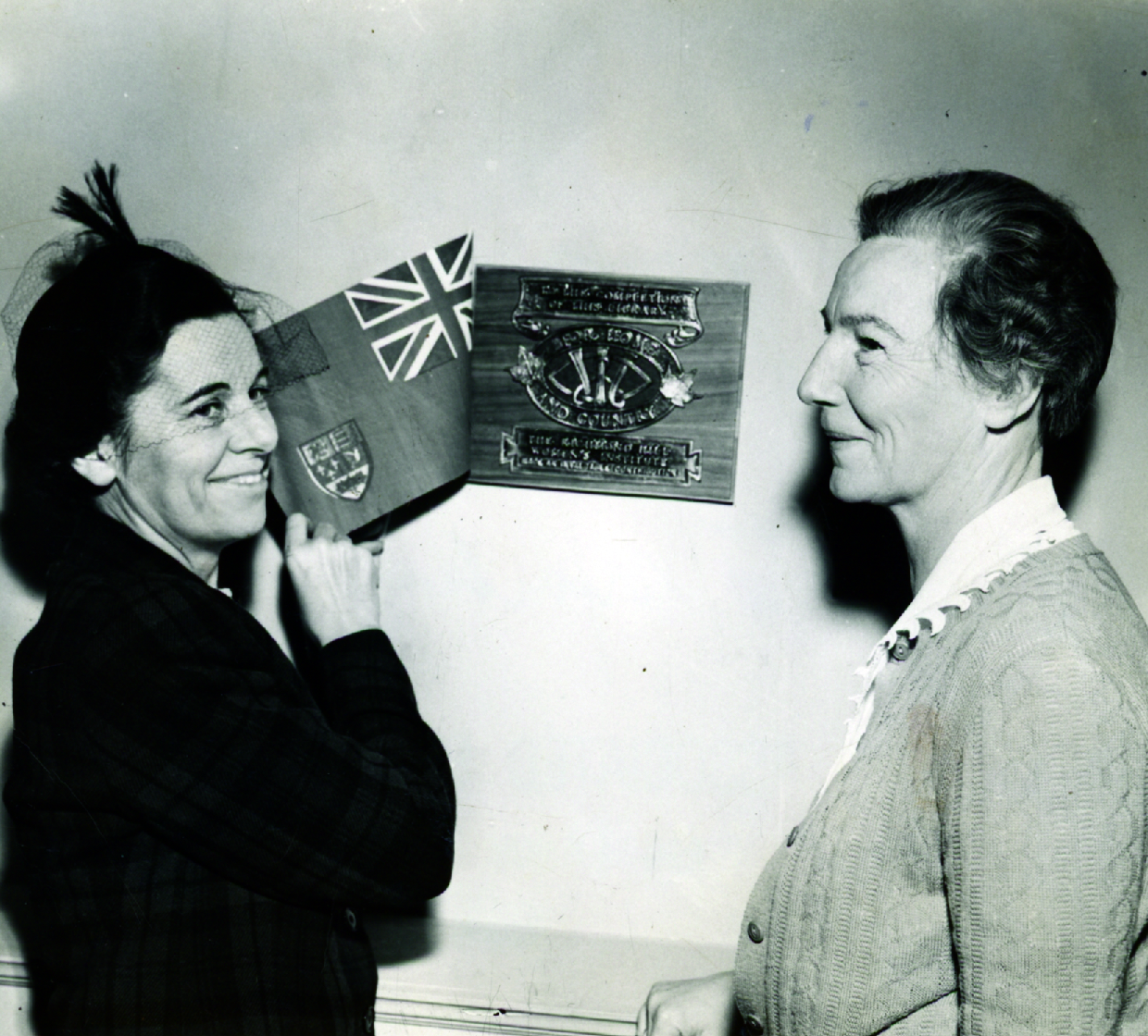 Mrs. H. H. MacKay unveiling the Women's Institute plaque with Edna Izzard representing the Library Board. The plaque commemorates the Institute's contribution to the library in 1949. (Richmond Hill Public Library, Tweedsmuir History Fonds)